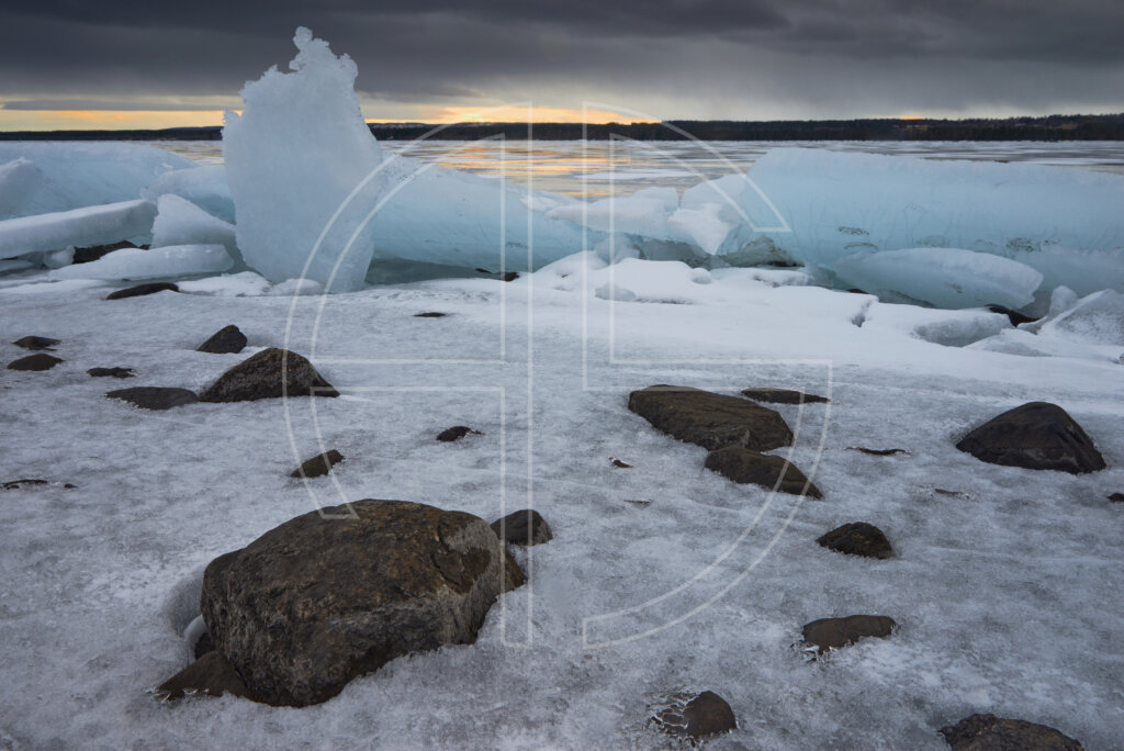 Sunset on a river with lots of ice. The skies brood in shadow.