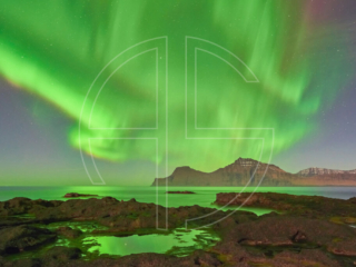 Northern Lights at the sea. The foreground has rocks with water puddles.
