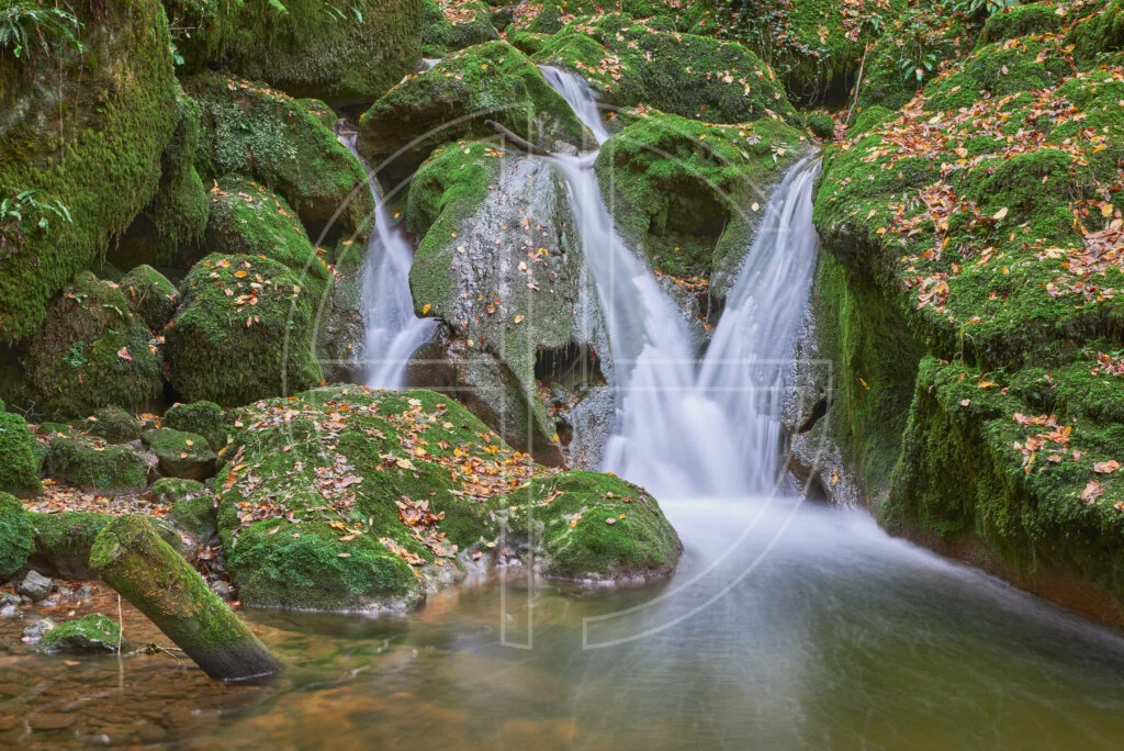 Mossy rocks and stones at a waterfall.
