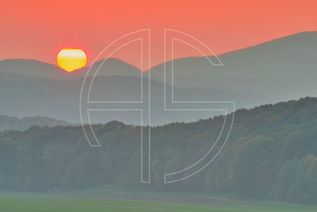 Forest, hills, and a hazy sunset.