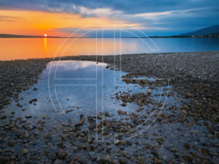 Down With The Sun Sunset at a beach. The foreground has a big water puddle.