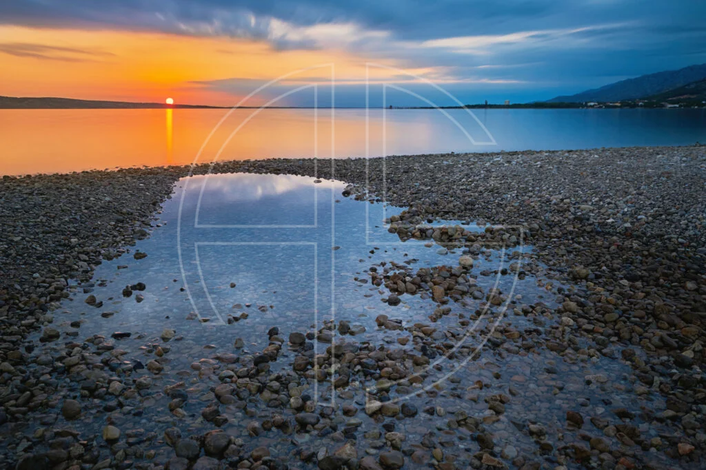 Down With The Sun Sunset at a beach. The foreground has a big water puddle.