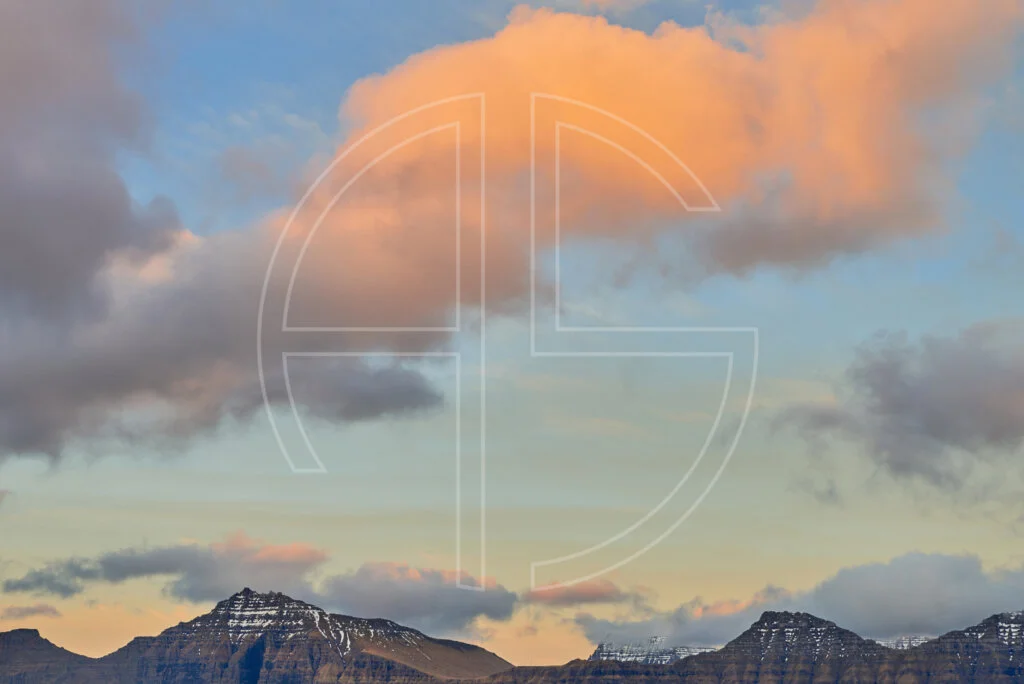 Mountains and a vast sky dotted with clouds glowing golden.