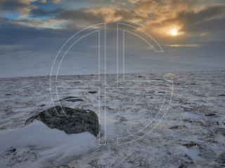 Sunset on a snow-covered hill on a grey and dark day.