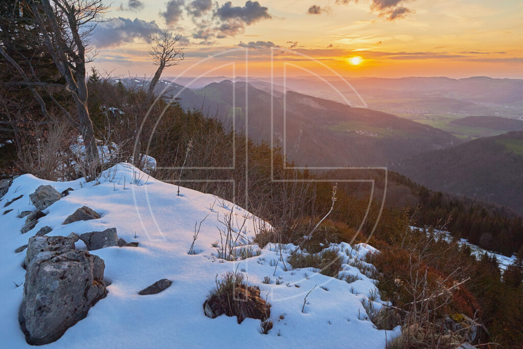 A golden sunset in a hilly landscape.