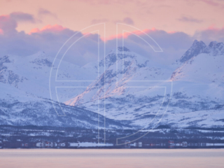 Pink dusk at the sea. Mountains loom in the background.