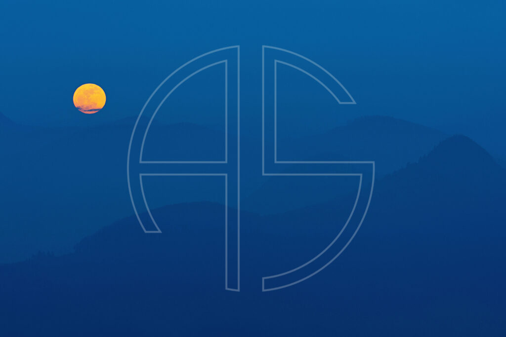 The full moon rises in a hilly, deep blue landscape.