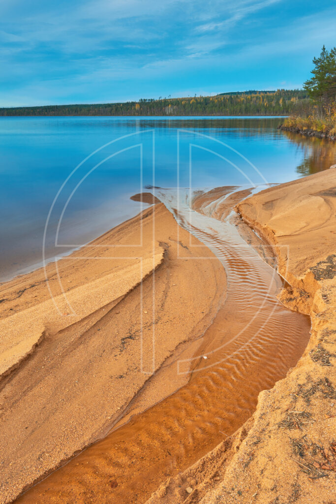 The sun lights the golden sand. A lake lies in the background.