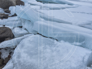 Sunset on a river with big slabs of ice. The skies brood in shadow.