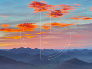 Hilly landscape and a sky with orange clouds.