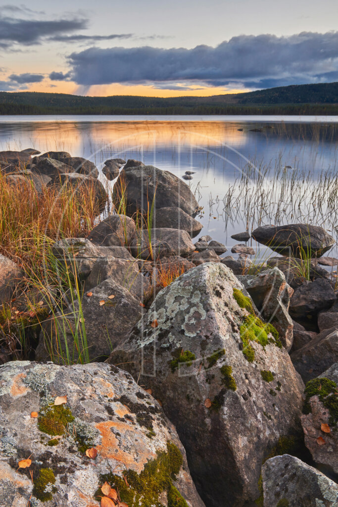 Big stones in the foreground and a lake in the background on an overcast day.