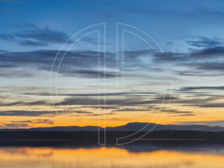 Dusk at a lake. In the background loom mountains.