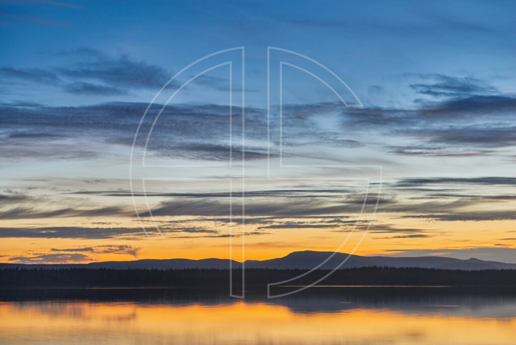 Dusk at a lake. In the background loom mountains.