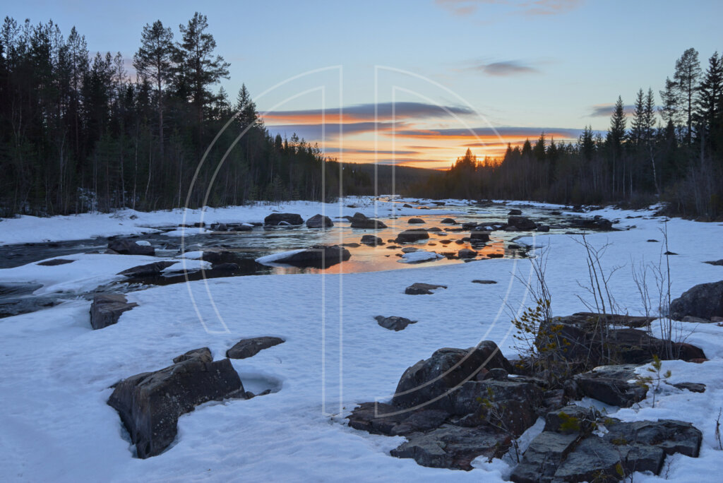 A snow-covered river at sunset.