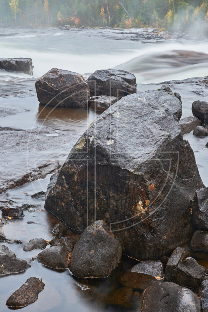 A big stone in the foreground and a wild river in the background.