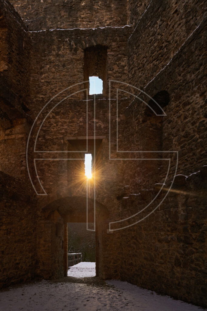 Success Is Failure Gilgenberg Castle with the sun shining through a window above the entrance door. Snow covers the ground.