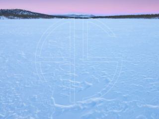 Dusk at a snow-covered frozen over lake.