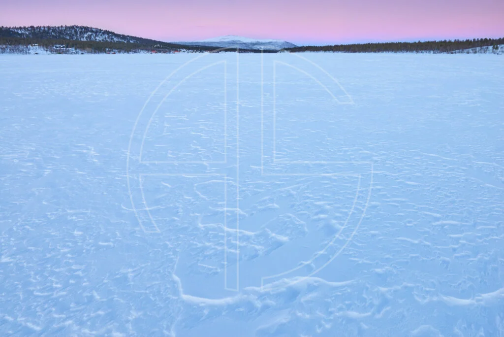 The Great Unwashed Dusk at a snow-covered frozen over lake.
