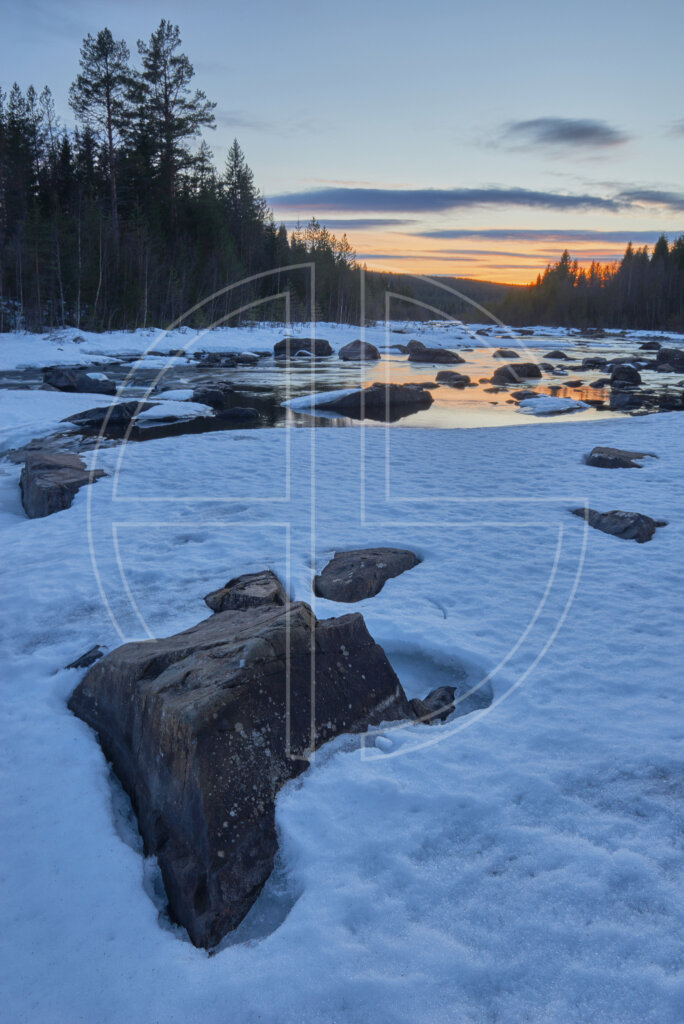 A snow-covered river at sunset.