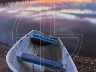 Sunset at a lake. A boat sits in the foreground.