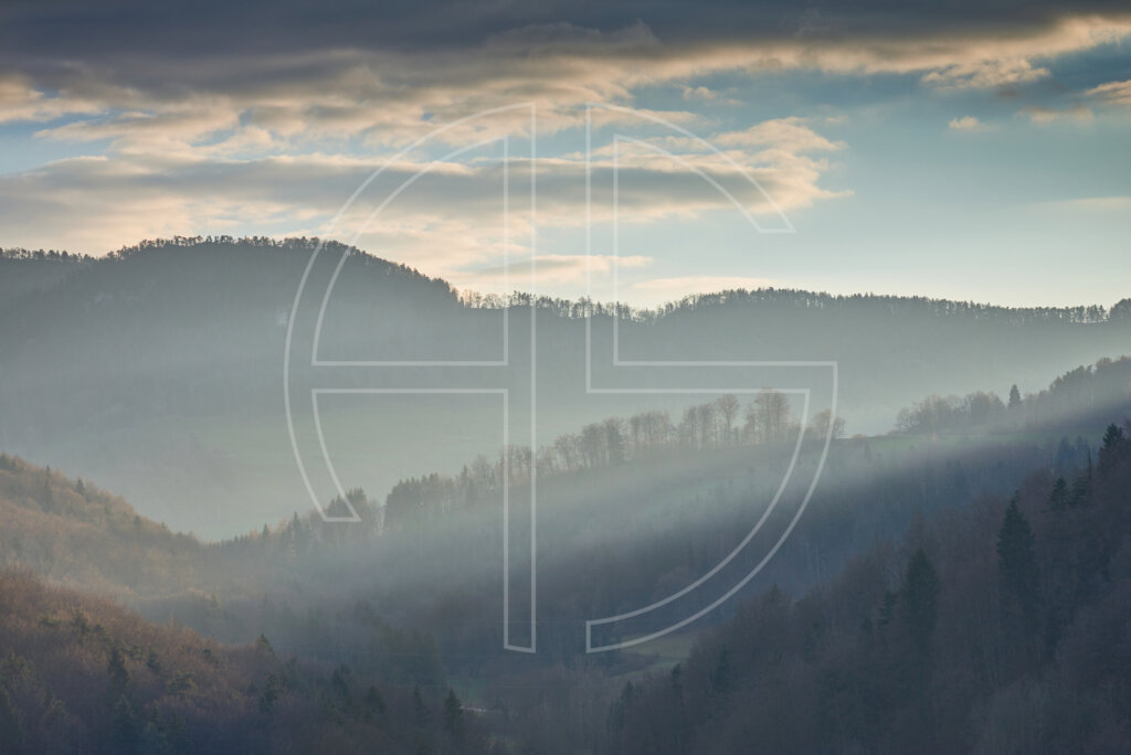 World That Melts Wooded hills and a beam of sunlight from the right.